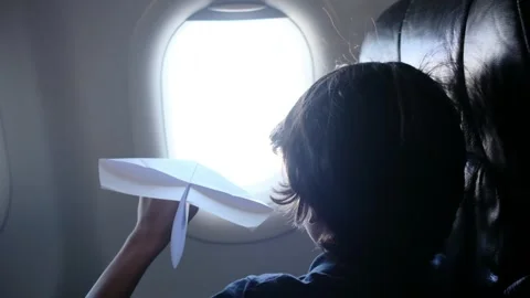 Child plays with a paper airplane inside an airplane looking out the window Stock Footage 252036721