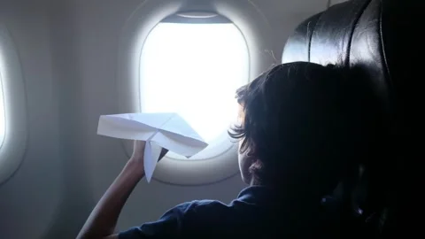 Child plays with a paper airplane inside an airplane looking out the window Stock Footage 252036722