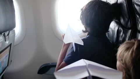 Child plays with a paper airplane inside an airplane looking out the window Stock Footage 252036731