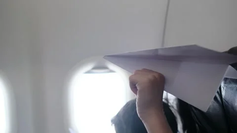 Child plays with a paper airplane inside an airplane looking out the window Stock Footage 252036742