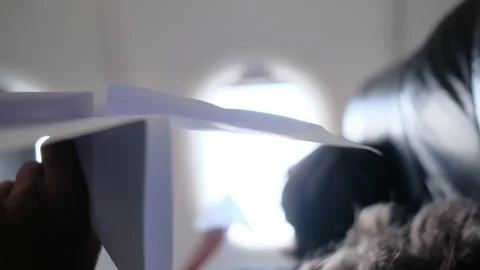 Child plays with a paper airplane inside an airplane looking out the window Stock Footage 252036757