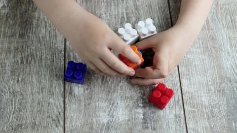 A child plays a plastic construction set on a wooden table Stock Footage 194539571