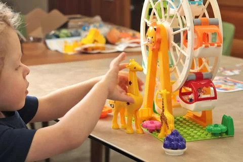 Child plays with a plastic constructor at home on table. Children and Stock Photos