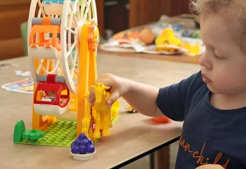 Child plays with a plastic constructor at home on table. Children and Stock Photos