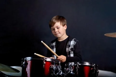 The child plays the red drums. Learning to play a musical instrument. Stock Photos
