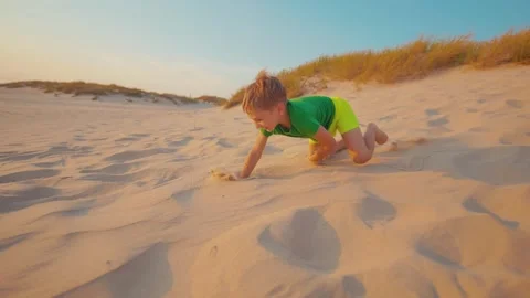 Child plays in sand on beach during sunset in summer Stock Footage 338301200