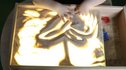 A child plays with sand on a light table Stock Footage 62076548