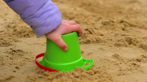 The child plays in the sandbox, builds a sand castle or Easter cake, picks up a  Video stock 190868609