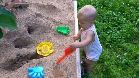 The child plays in the sandbox hd Video stock 79931676