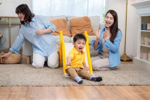 Child plays on slide while two adults cheer in living room during the day Foto stock