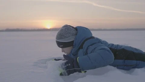 A child plays in the snow at sunset. Fun and games in the fresh air 스톡 동영상 83385961