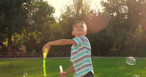 Child plays with soap bubbles in nature. Child boy having fun playing Stock Footage 239910482