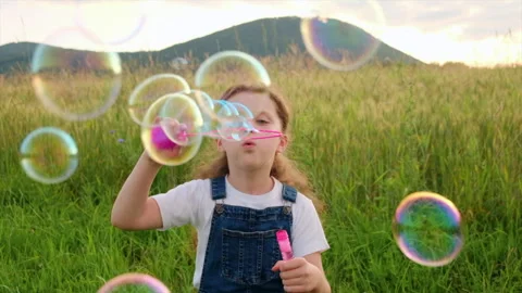 Child plays with soap bubbles in nature Stock Footage 246699741