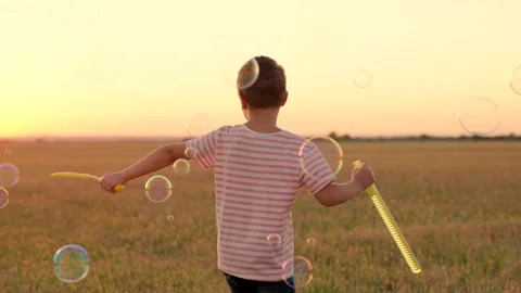 Child plays with soap bubbles in park in nature. Happy childhood concept. Child Stock Footage 237645703