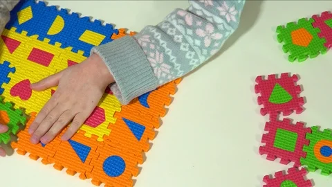 The child plays with soft multi-colored puzzles. Soft mat in the form of piec Stock Footage 120909776