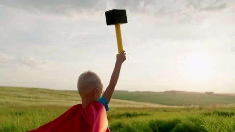 Child plays superhero from comic book, child holds hammer in his hand. Child Stock Footage 236300306