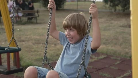 A child plays with the swing on the playground Stock Footage 255203980