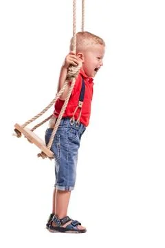 Child plays on a swing while smiling with joy during a fun moment indoors in Stock Photos