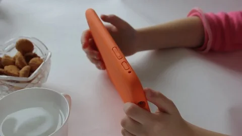 Child plays a tablet game on a kitchen table Stock Footage 72800219