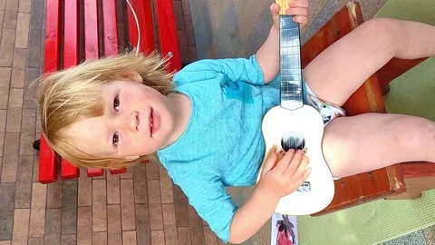 The child plays the ukulele. Video stock 226730557