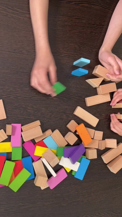The child plays using wooden cubes, creating towers and buildings, Stock Footage 244656632