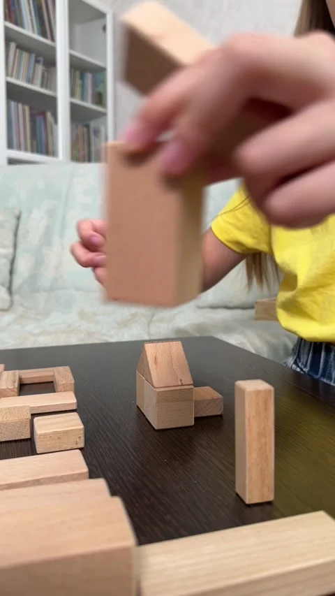 The child plays using wooden cubes, creating towers and buildings, Stock Footage 244656646