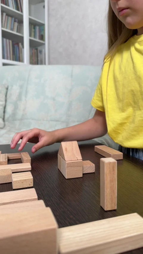 The child plays using wooden cubes, creating towers and buildings, Stock Footage 244656663