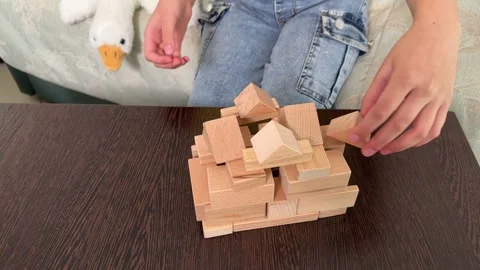 The child plays using wooden cubes, creating towers and buildings, Stock Footage 244656684