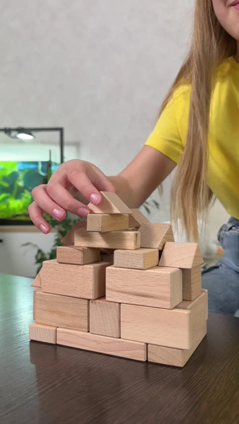 The child plays using wooden cubes, creating towers and buildings, Stock Footage 244656702