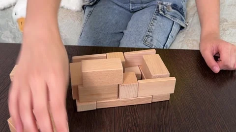 The child plays using wooden cubes, creating towers and buildings, Stock Footage 244656755