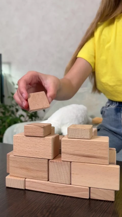 The child plays using wooden cubes, creating towers and buildings, Stock Footage 244656836