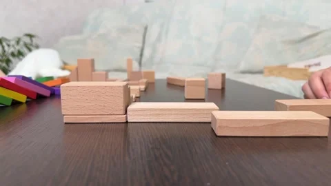 The child plays using wooden cubes, creating towers and buildings, Stock Footage 244656864