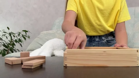 The child plays using wooden cubes, creating towers and buildings, Stock Footage 244656915