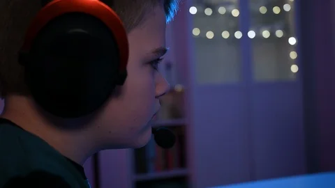 Child plays video games while wearing headphones - close up of face Stock Footage 100794436