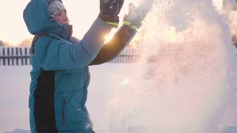 A child plays in the winter outdoors, throws snow to the top. Active outdoor Vidéo 85128280