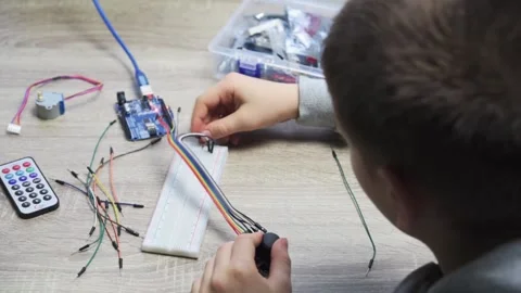 A child plugging cables to sensor chips while learning arduino coding and Stock Footage 167843930