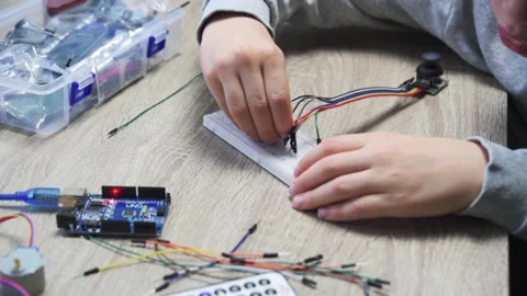 A child plugging cables to sensor chips while learning arduino coding and Stock Footage 167881218