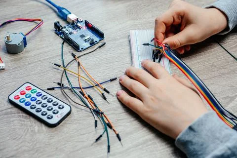 A child plugging cables to sensor chips while learning arduino coding and Stock Photos
