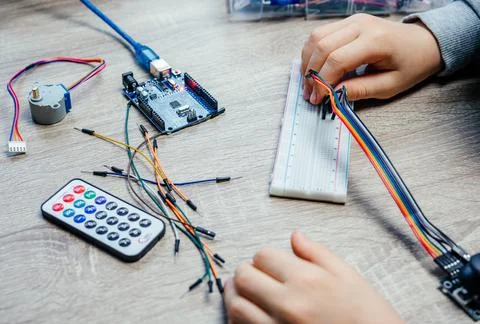 A child plugging cables to sensor chips while learning arduino coding and 스톡 사진