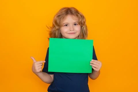 Child pointing on empty green sheet of paper, isolated on yellow background Stock Photos