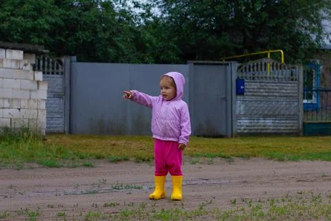 The child points to the side while standing outside on a dirty road. A child Stock Photos