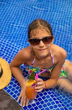 A child in the pool drinks a cocktail. Selective focus. Stock Photos
