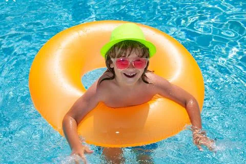 Child in pool on inflatable ring. Kid swim with orange float. Healthy outdoor 写真素材