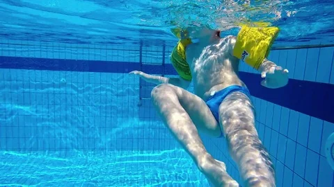 The child in the pool to learn to swim. Shooting under water. Stock Footage 79825319