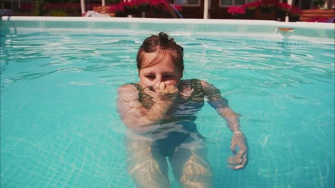 Child in pool, playful gesture, sunlight and water splash Stock Footage 334161744