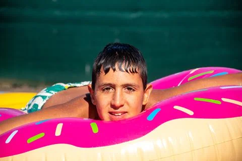 Child in pool on top of float relaxed and wet looking straight ahead Stock Photos