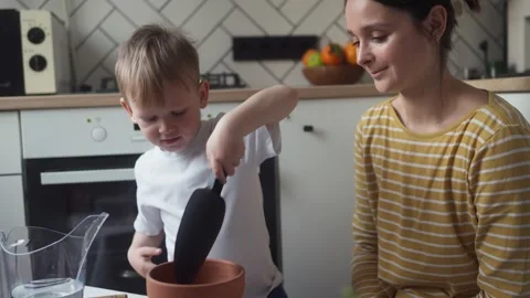 Child pouring drainage material into pot using shovel before planting seedlings Stock Footage 331438082