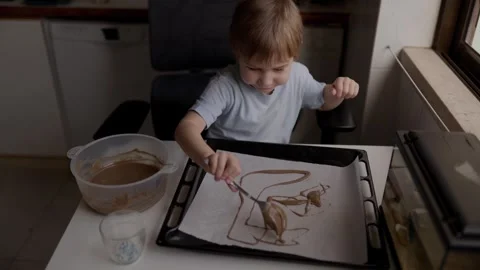 Child pouring melted chocolate on baking sheet Stock Footage 316249777