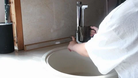 The child pours clean drinking water filtered from the tap into a glass and Vidéo 247178582