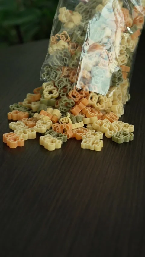 A child pours a pack of bear-shaped pasta onto the table Stock Footage 317917689
